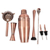 Copper cocktail set including shaker, strainer, jigger, and other tools on a white background
