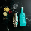 Skull shaped Cocktail shaker, Rusty Barrel Gin bottle, and ingredients on a dark marble surface