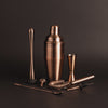 A set of brushed copper cocktail shaker, muddler, bar spoon, strainer, pourers, and a double jigger