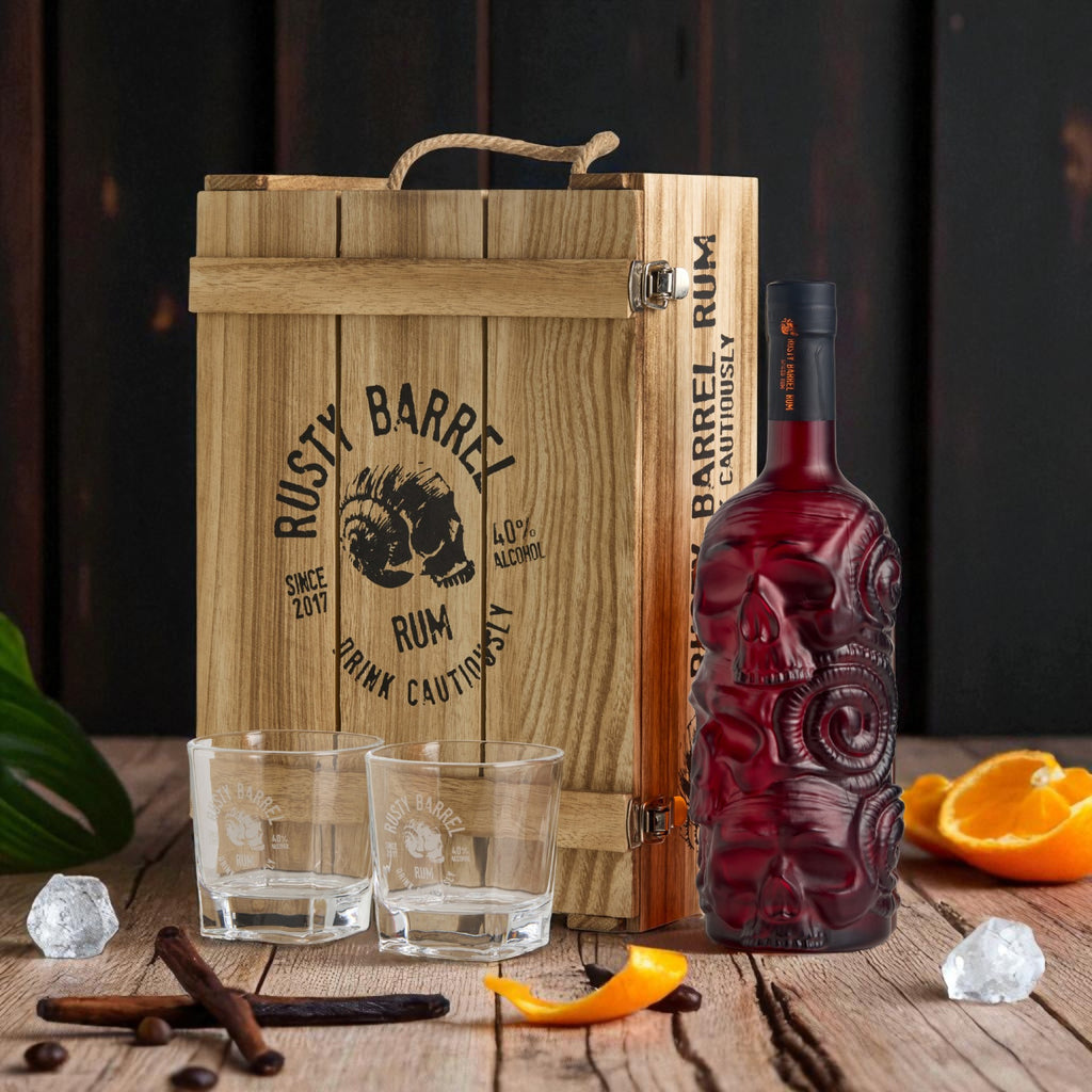 Rusty Barrel Spiced Rum bottle and Gift Box with cocktail glasses on a wooden surface with a rustic background