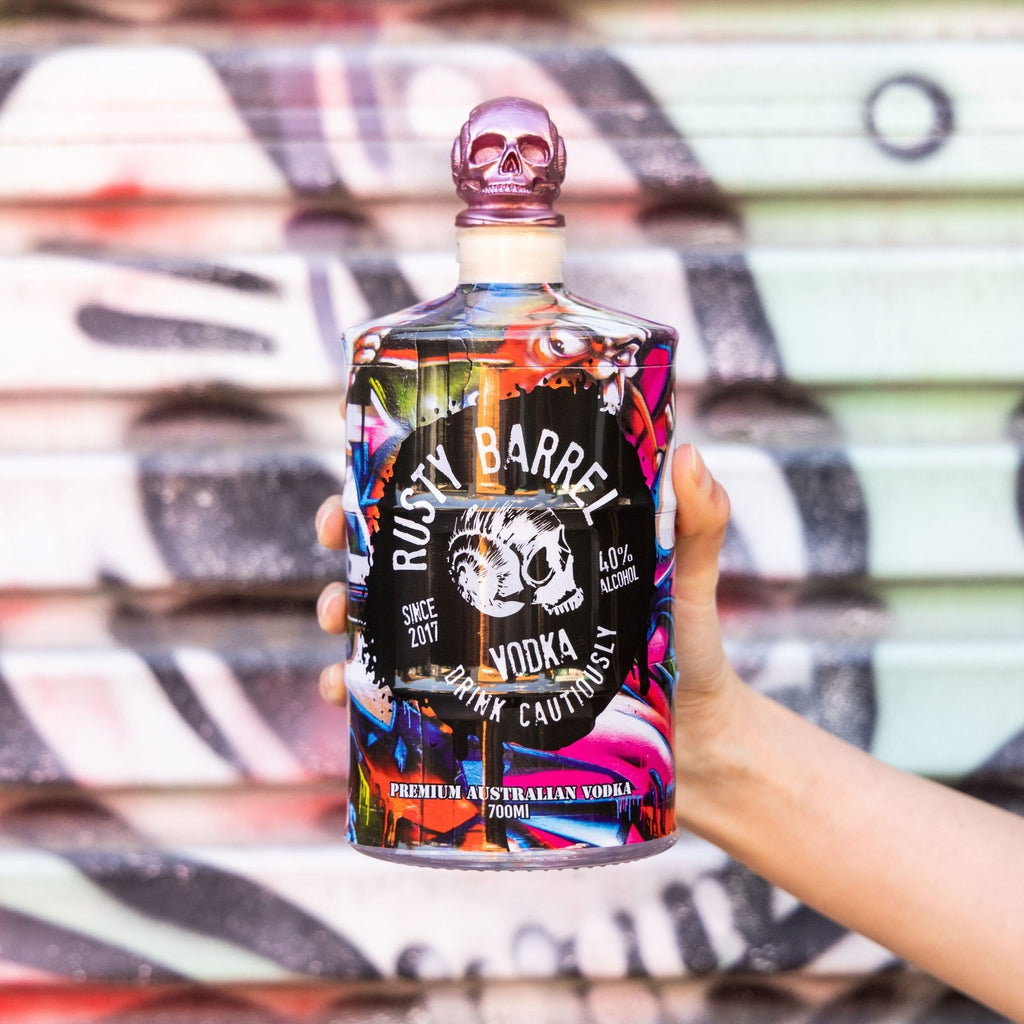 Bottle of Rusty Barrel Vodka 700ml held in front of a colorful, abstract background