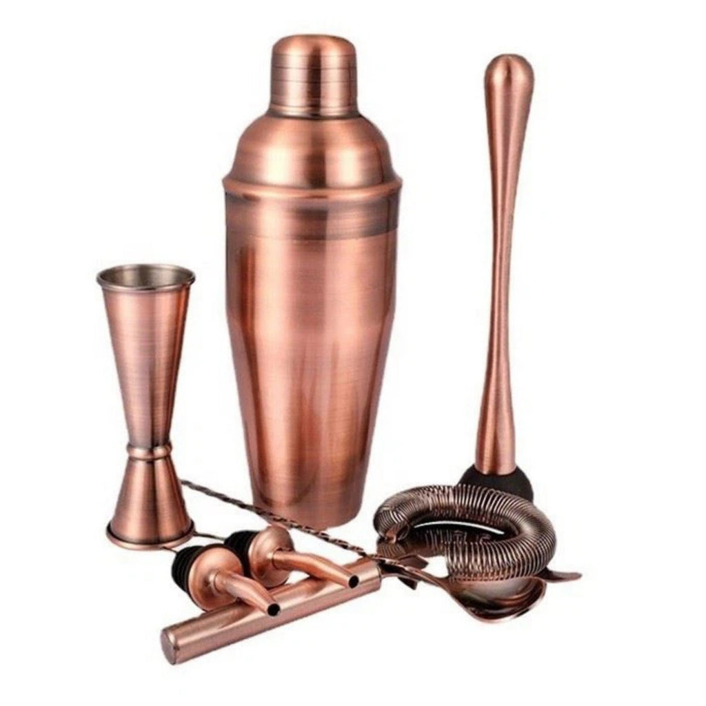 Copper cocktail shaker set with jigger, bar spoon, and strainer on a white background