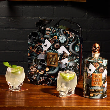 Rusty Barrel Vodka bottle and packaging on a wooden surface with skull glasses.