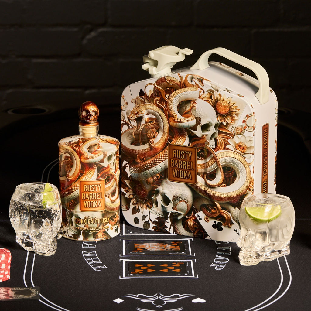 Rusty Barrel Vodka bottle and packaging with skull-themed glasses and playing cards on a black background