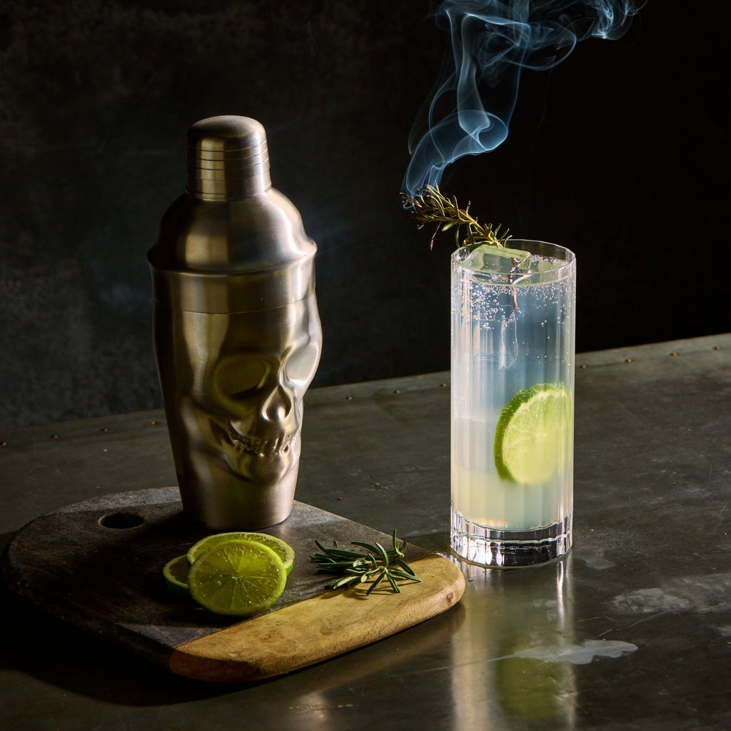 Rusty Barrel Spirits Cocktail shaker and glass with lime and rosemary on a dark surface
