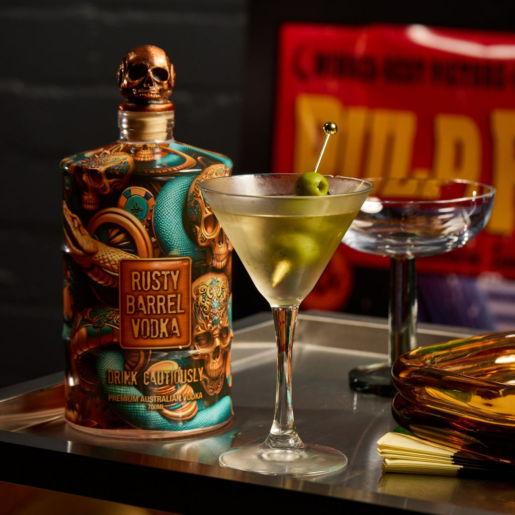 Rusty Barrel Vodka bottle with a cocktail garnished with a olive on a bar counter.