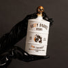 Bottle of Rusty Barrel Vodka 700ml Matte White held by a gloved hand against a dark background