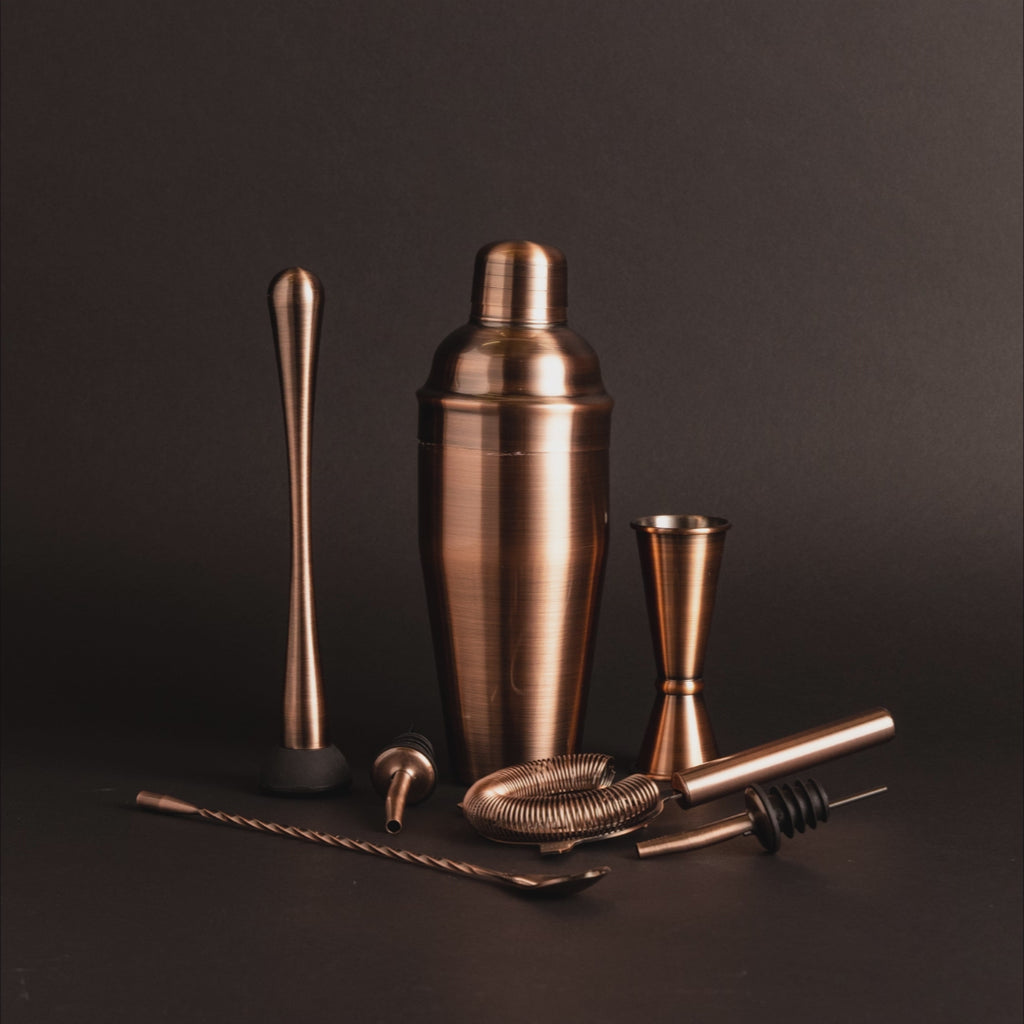 A set of brushed copper cocktail shaker, muddler, bar spoon, strainer, pourers, and a double jigger